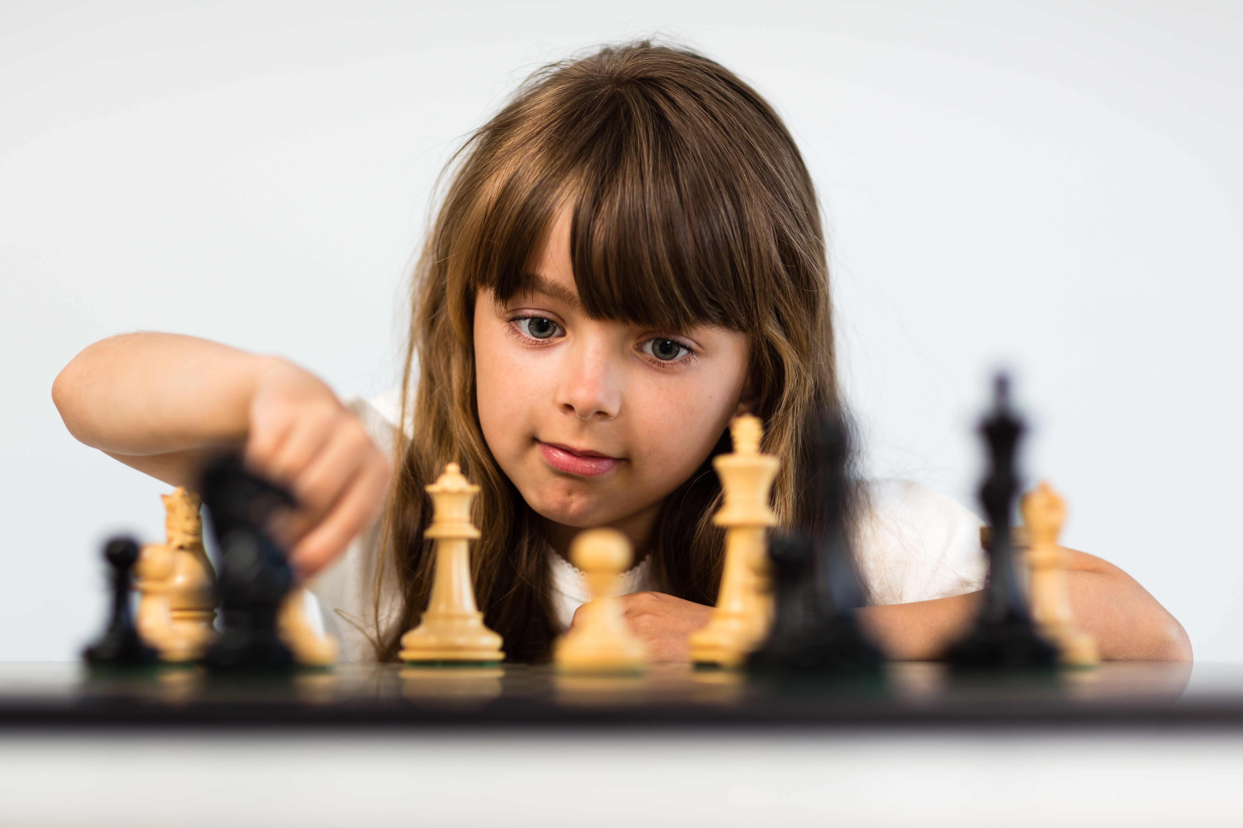 Young caucasian girl with long hair playing a game of chess.